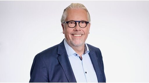 Portrait von Tilman Rauh vor neutralem Hintergrund