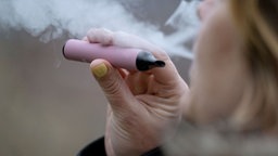 Eine Frau pustet den Rauch einer Vape aus 