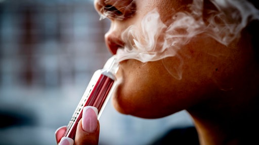 Eine junge Frau raucht eine Vape 