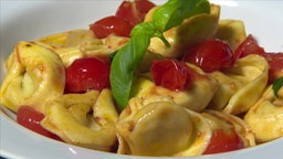 Fleisch-Tortelloniwerden mit Tomaten und Basilikum serviert.