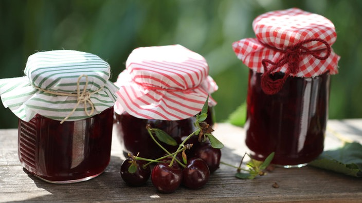 Drei Gläser mit Kirschkonfitüre stehen auf einem Tisch