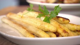 Eine flache weiße Schale mit gegrilltem Spargel