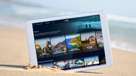 Tablet mit der Startseite der Mediathek-Themenwelt Reisen steckt im Sand