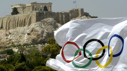 Die Olympische Fahne weht vor der Akropolis in Griechenland.