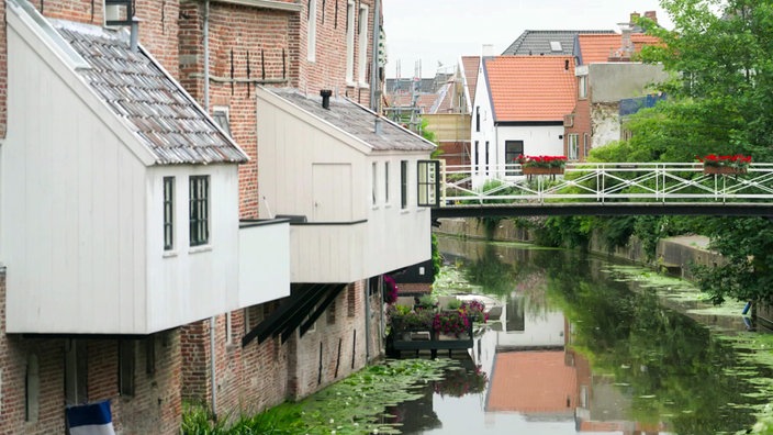 Kleine Holzanbauten an Backsteingebäuden über einem Fluss
