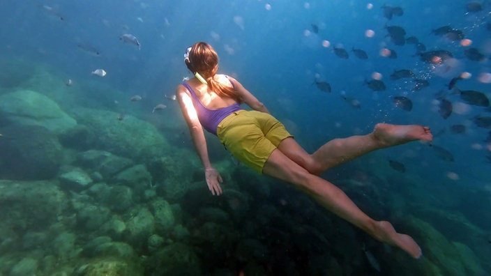 Tamina Kallert taucht im Meer zwischen Fischen
