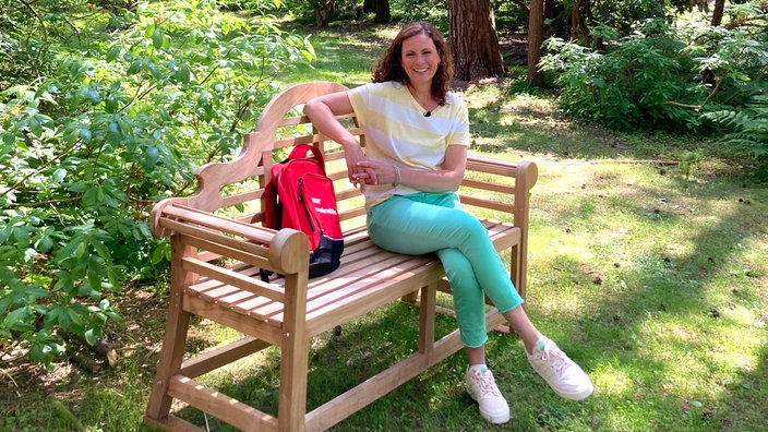 Anne Willmes sitzt auf einer Holzbank im Rhododendron-Waldpark Hobbie in Westerstede