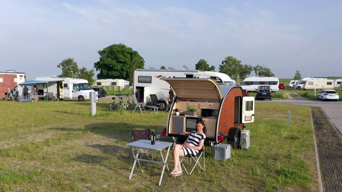 Anne Willmes sitzt an einem Campingtisch vor ihrem kleinen Wohnwagen
