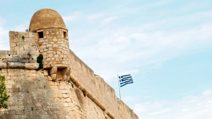 Die griechische Flagge über einem historischen Mauerwerk