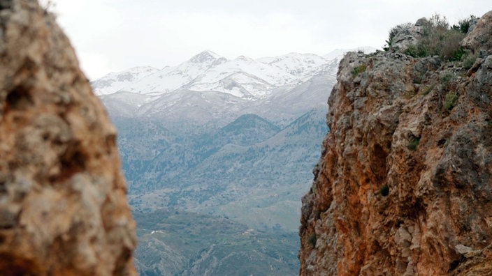 Blick zwischen zwei Felsen hindurch auf weit entfernte schneebedeckte Berge
