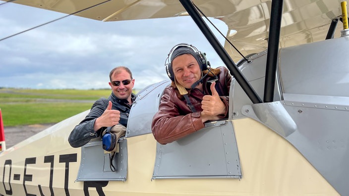 André Gatzke (r) und ein Pilot sitzen in einem historischen Flugzeug