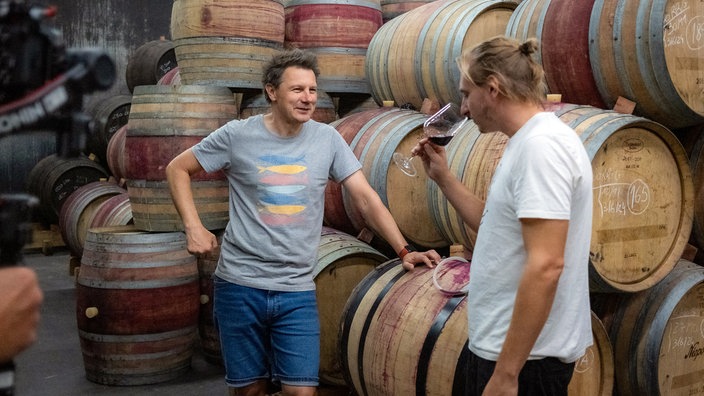 André Gatzke (l) und Winzer Daniel Niepoort stehen vor Holzfässern
