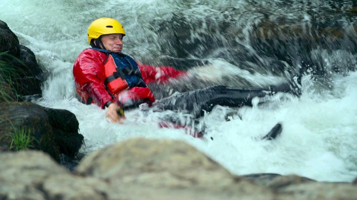 André Gatzke mit gelben Helm rutscht beim Rivertrekking durch das Flussbett