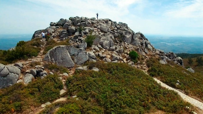 Fotografierender Tourist steht auf felsigem Gipfel des Monte Fóia