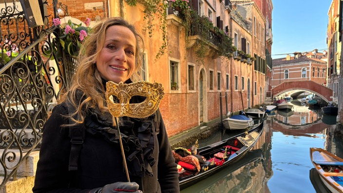 Tamina Kallert mit einer  Maske in der Hand an einem Kanal