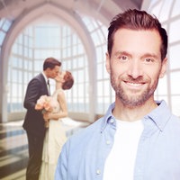 Daniel Aßmann steht in einem Anzug in einer Kirche vor einem Banner, auf dem "Just Married" steht.