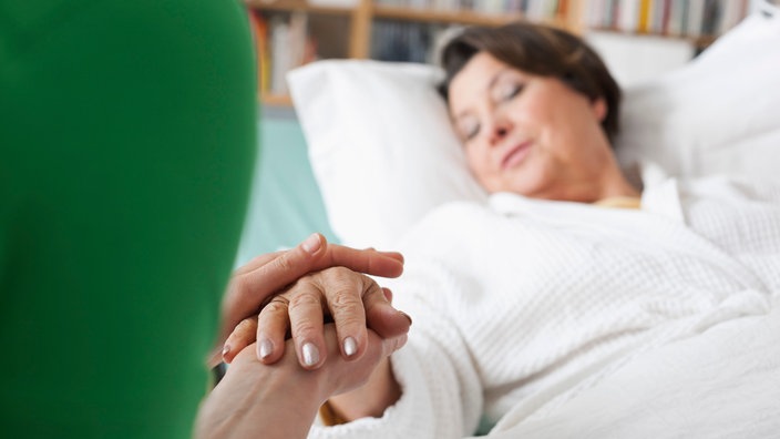 Eine aältere Dame liegt zuhause in ihrem Pflegebett.
