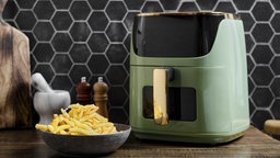 Symbolbild Airfryer: Eine Luftfritteuse befindet sich auf einer Holzarbeitsplatte in einer Küche. 