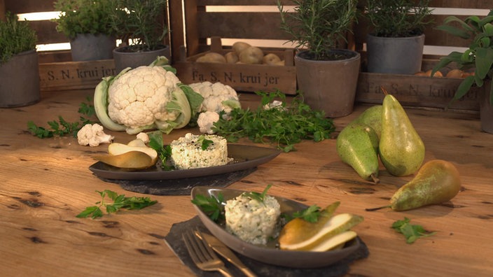 Das Bild zeigt zwei Teller mit dem angerichteten Blumenkohlsalat mit Birne. 