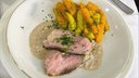Zwei Scheiben Kalbsschmorbraten mit Möhrengemüse auf einem Teller angerichtet