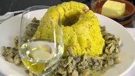 Gestürzter Kartoffelpudding aus Guglhupfform, davor ein Glas Weißwein