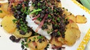 Gebratenes Kabeljaufilet mit Bratkartoffeln auf einem Teller angerichtet