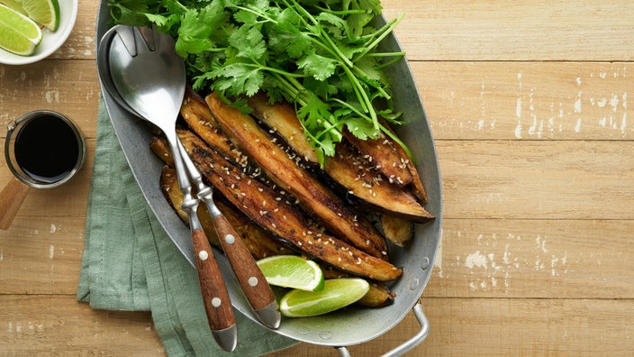 Symbolfoto: Gebackene Aubergine zusammen mit Koriander auf einem Teller serviert.