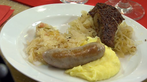 Sekt- oder Champagner-Kraut von Dietmar Bär mit Kartoffelpuree und Wurst auf einem Teller angerichtet