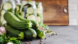 Zucchinis liegen mit Knoblauch und Pfeffer auf dem Tisch. 