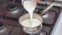 Milch wird in einen Topf geschüttet.