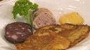 Reibekuchen mit Wurst und Senf herzhaft auf einem Teller angerichtet