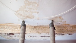 Eine Wand, aus der zwei Rohre rauskommen. An der Wand sind Wasserflecken zu sehen