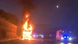 brennender Lkw auf dem Standstreifen einer Autobahn bei Gelsenkirchen, daneben steht ein Feuerwehrwagen