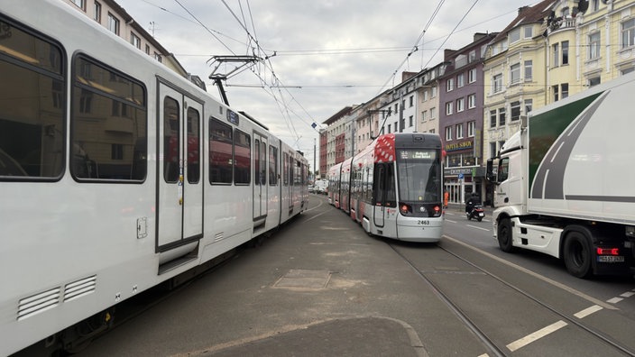 Auf einer viel befahrenen Straße fahren zwei Straßenbahnen in die Richtung der Kamera. Ein LKW fährt in die andere Richtung. 