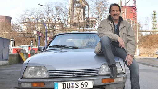 Schimmi sitzt in Duisburg auf der Motorhaube seines Citroen