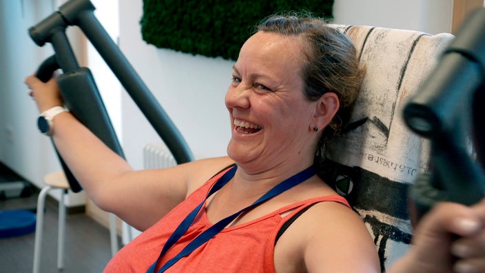 Frau sitzt auf Fitnessgerät.