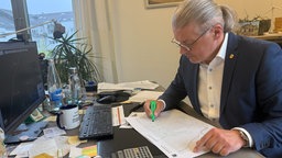 Bürgermeister von Simmerath Bernd Goffart (CDU) sitzt an seinem Schreibtisch und markiert etwas mit einem Textmarker.