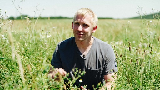 Werner Klemme sitzt in seinem Unkraut-Feld