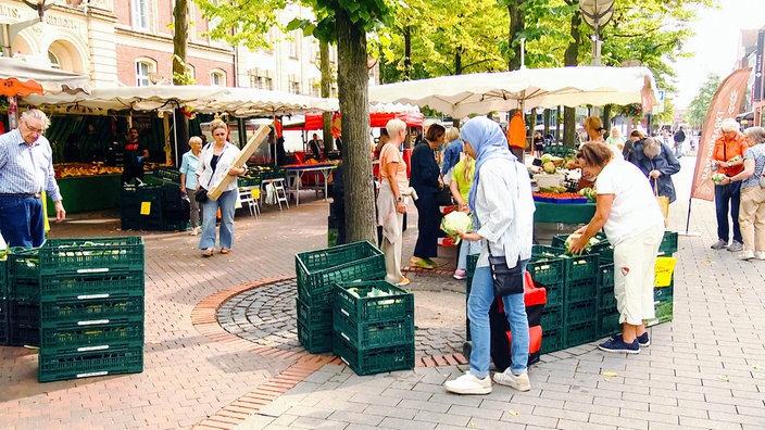 Mehrere Menschen sehen sich die Produkte an den Ständen des Bauernmarkts in der Duisburger Innenstadt an.
