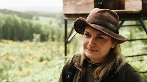Martina Rohn steht vor einem Jagdhochsitz. Sie lächelt.