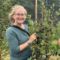 Franziska und Ralph Schulze Mönking stehen neben einem Strauch mit reifen Junibeeren