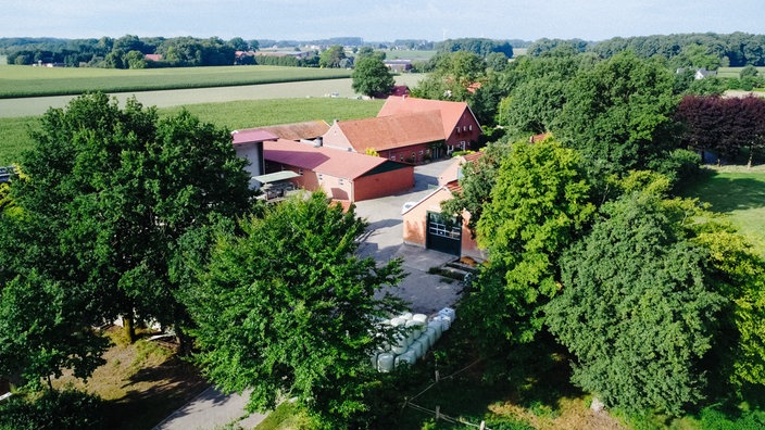 Eine Luftaufnahme eines Bauernhofes. Der Hof ist umgeben von Bäumen.