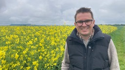 Mit kurzem Haar und Brille lächelt der Landwirt breit.