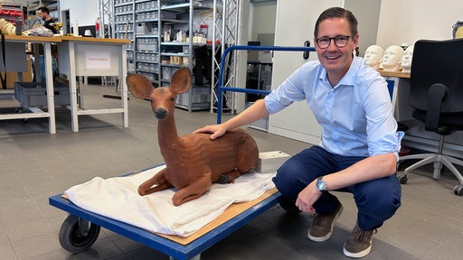 Peter Schimmelpfennig hockt neben einem Reh-Dummy.