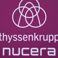 Ein rosanes Logo als Schild, auf dem "Thyssenkrupp Nucera" steht.