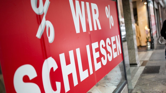 Ein rotes Plakat mir der Aufschrift "wir schließen" an einem Ladenlokal