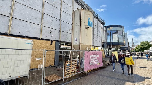 Das ehemalige Kaufhof-Gebäude von außen. Die Fassade ist komplett ab und man sieht die Betonplatten darunter.