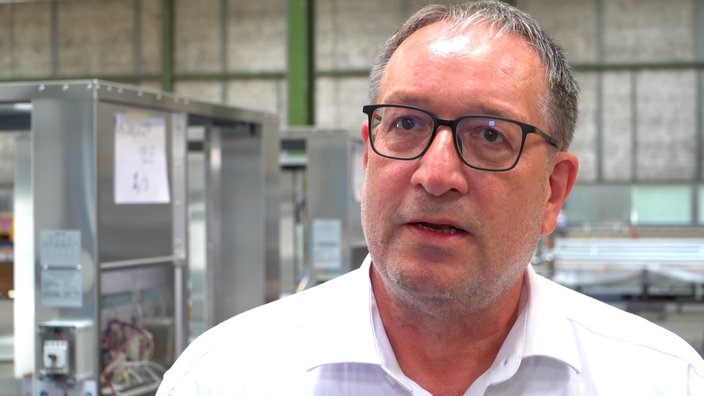 Ein Mann in einem weißen Hemd steht in einer Fabrikhalle