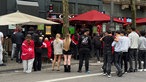 Fußballfans schauen draußen stehend das WM-Spiel 
