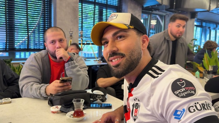 Mehmet Sanli sitzt neben weiteren Personen.